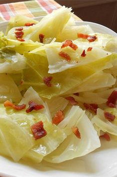 a white plate topped with lettuce and bacon on top of a checkered table cloth