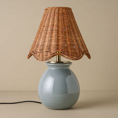 a blue lamp with a wicker shade on the top is sitting on a table