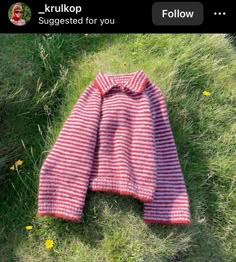 a red and white striped sweater laying on the grass