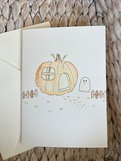 a white card with a pumpkin and ghost drawn on it, next to an envelope