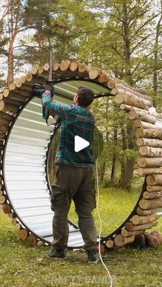 a man standing in front of a circular structure made out of logs