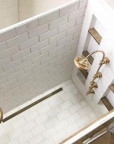 a bathroom with white tile and gold fixtures on the shower head, tub, and toilet