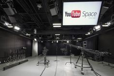 an empty room with microphones and lights in front of a large screen that says youtube space