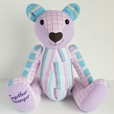 a purple teddy bear sitting on top of a white table