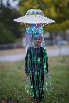 a young boy wearing a costume made out of plastic beads and an umbrella on top of his head