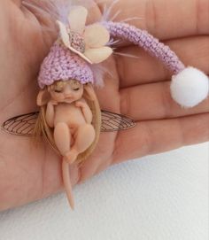 a hand holding a tiny fairy figurine on it's thumb and wearing a pink hat