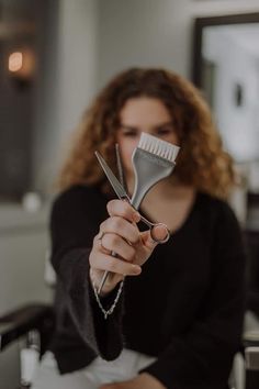 a woman holding a comb and scissors in her hand