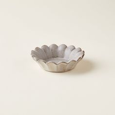 a white bowl sitting on top of a table next to a white wall and floor