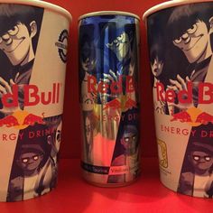 three red bull energy drinks are shown in front of an orange background and the bottom one is blue