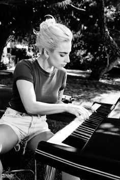 a woman sitting at a piano in the grass