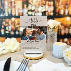 a table with a sign that says table one on it and flowers in the background