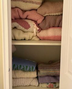 an open closet filled with blankets and pillows