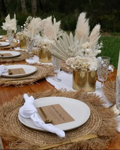 the table is set with place settings, napkins and vases filled with flowers