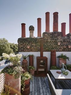 an outdoor living area with potted plants and brick chimneys