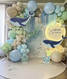 an ocean themed birthday party with balloons, streamers and dolphin decorations on the wall