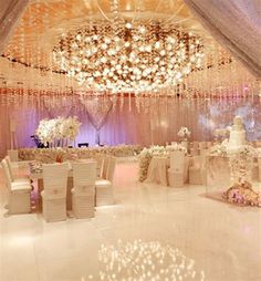 an elegant wedding reception with chandeliers and white linens on the ceiling, decorated with flowers