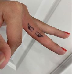 a person's hand with an angel wing tattoo on the left side of their finger