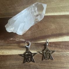 two star charms sitting on top of a wooden table next to a crystal point and rock