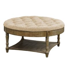 a round wooden coffee table with a beige upholstered cushion on it's top