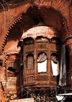 an old window with curtains hanging from it