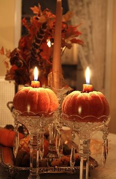 two pumpkins sitting on top of a table with candles in the middle of them