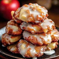 a stack of glazed donuts sitting on top of a plate next to an apple