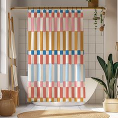 a colorful shower curtain in a bathroom next to a potted plant