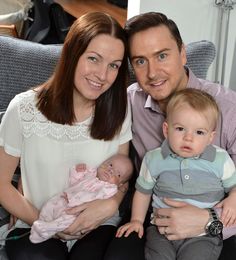 a man and woman sitting next to a baby