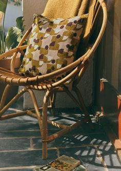 a wicker rocking chair with a cushion on the floor next to a potted plant