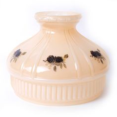 a cream colored vase with black flowers on the top and bottom, sitting against a white background