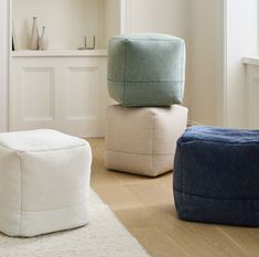 three bean bags stacked on top of each other in front of a white wall and wooden floor