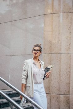 a woman is walking down the stairs while holding a book in her hand and looking up