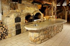 an outdoor kitchen with stone ovens and wood logs