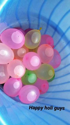 a blue bowl filled with lots of pink and yellow balloons