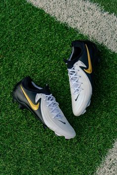 a pair of black and yellow nike shoes on the grass next to a white line