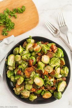 brussel sprouts with bacon and parsley in a black bowl on a white table