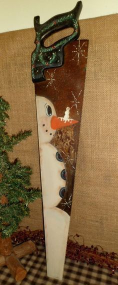 a snowman is standing in front of a christmas tree with a pair of scissors