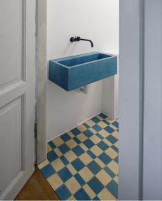 a blue sink sitting in the middle of a bathroom next to a doorway with a checkered floor