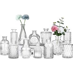 a group of vases and flowers sitting on a table next to each other in front of a white background