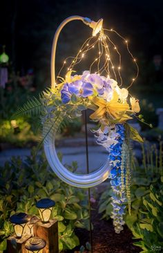 an outdoor decoration with flowers and lights in the shape of a circle on a pole