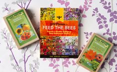 three seed packets sitting next to each other on top of a flower covered tablecloth