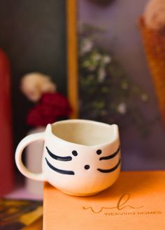 a white cat mug sitting on top of an orange box