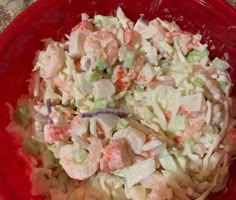 a red bowl filled with coleslaw salad on top of a table