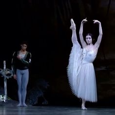 two ballerinas are performing on stage with one holding her arms in the air