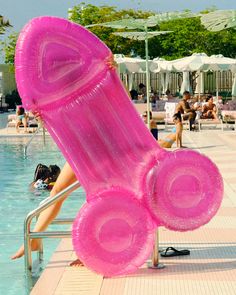 a woman sitting on a chair next to a swimming pool with giant inflatable objects