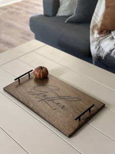 a wooden tray with a pumpkin on it sitting on top of a white coffee table