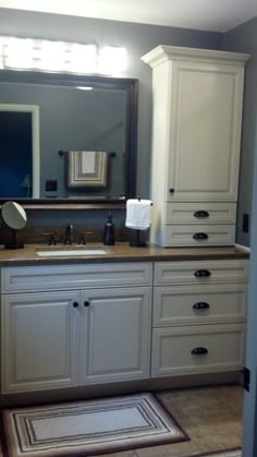 a bathroom with white cabinets and a large mirror