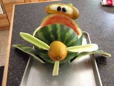 a watermelon shaped like a frog sitting on top of a piece of fruit