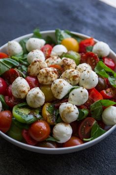 a salad with mozzarella and tomatoes in a white bowl on a blue surface