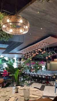 a restaurant with tables, chairs and plants hanging from the ceiling